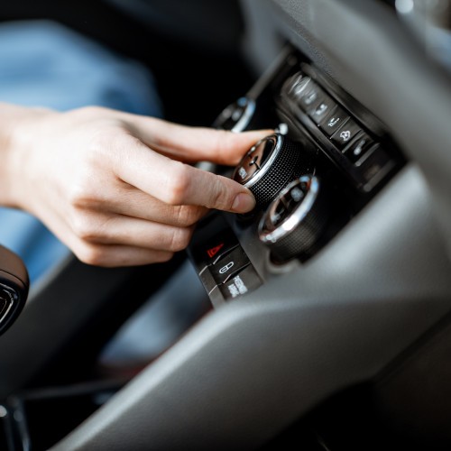 a hand turning the ac knob on a car dashboard